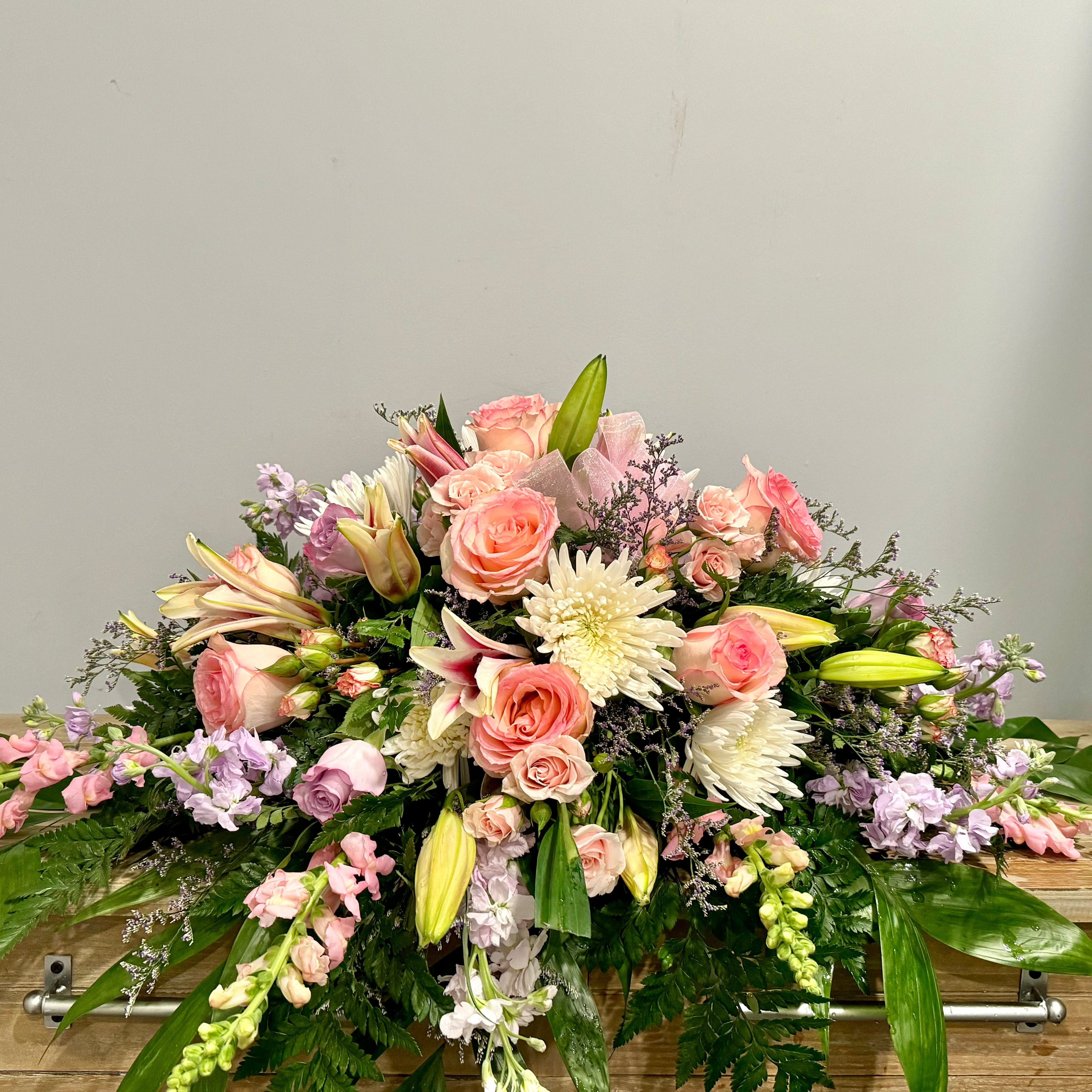 A light pink and white casket spray.
