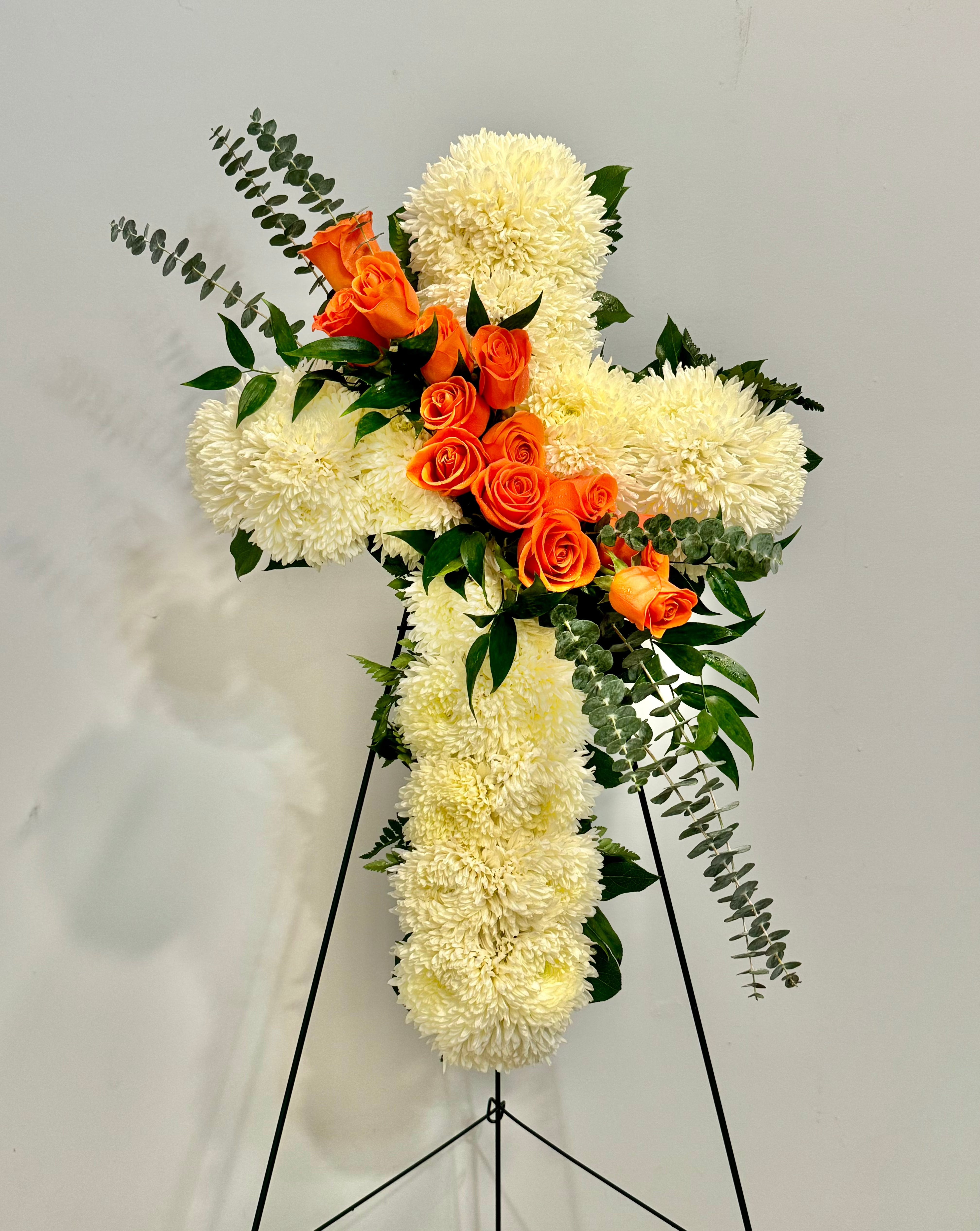 A white cross spray with orange roses.