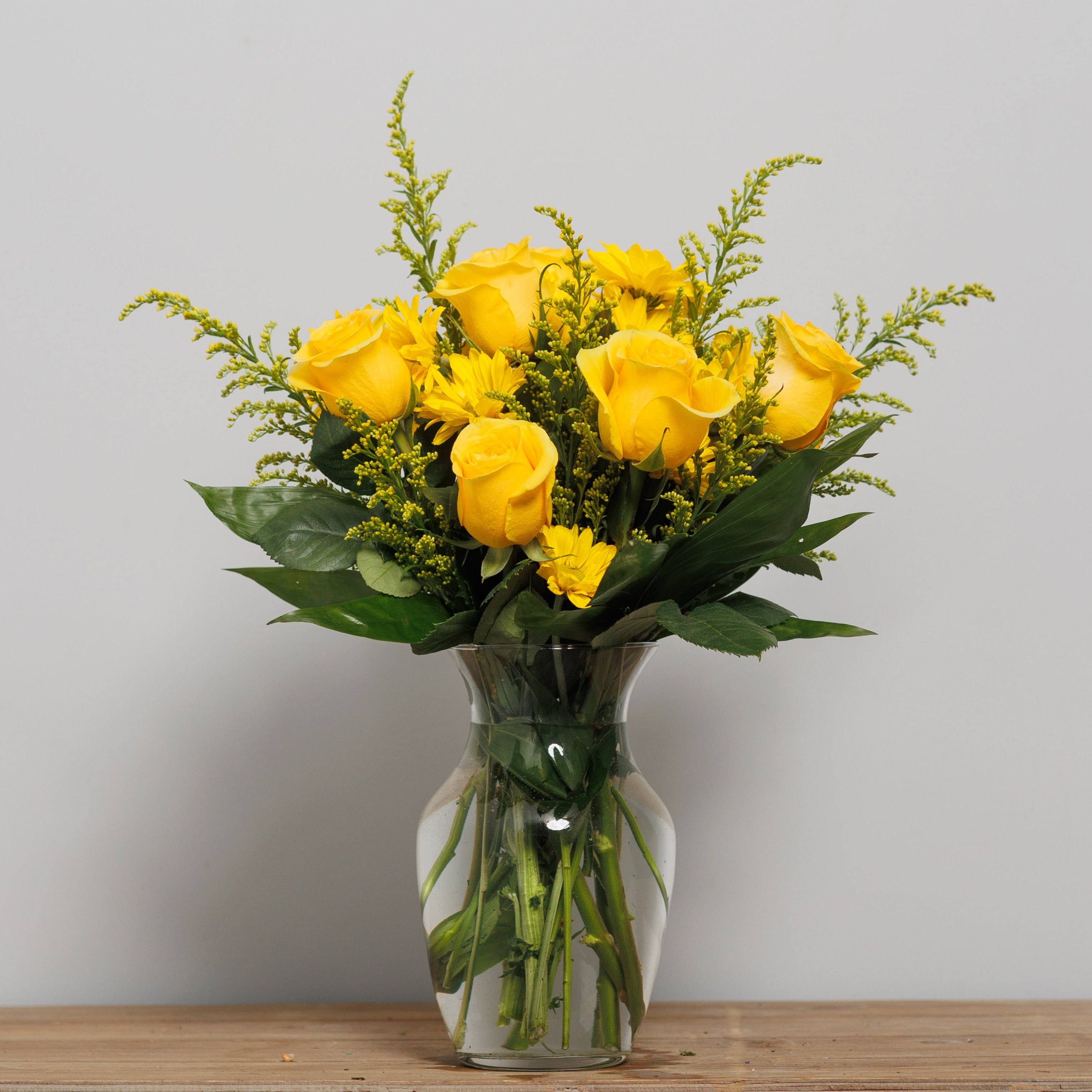 Yellow roses and yellow daisies in a vase.