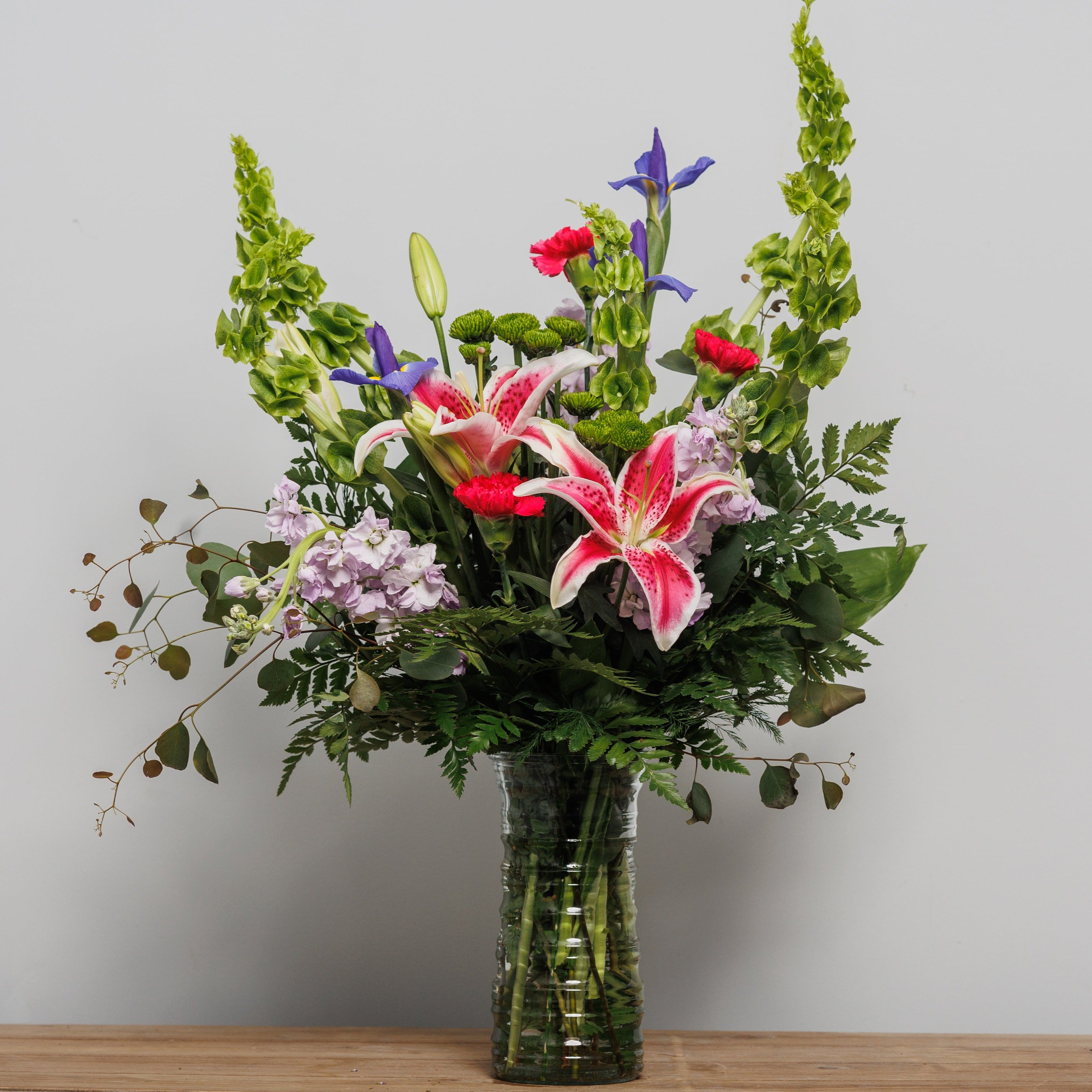 A flower arrangement with iris, bells of Ireland and stargazer lilies.