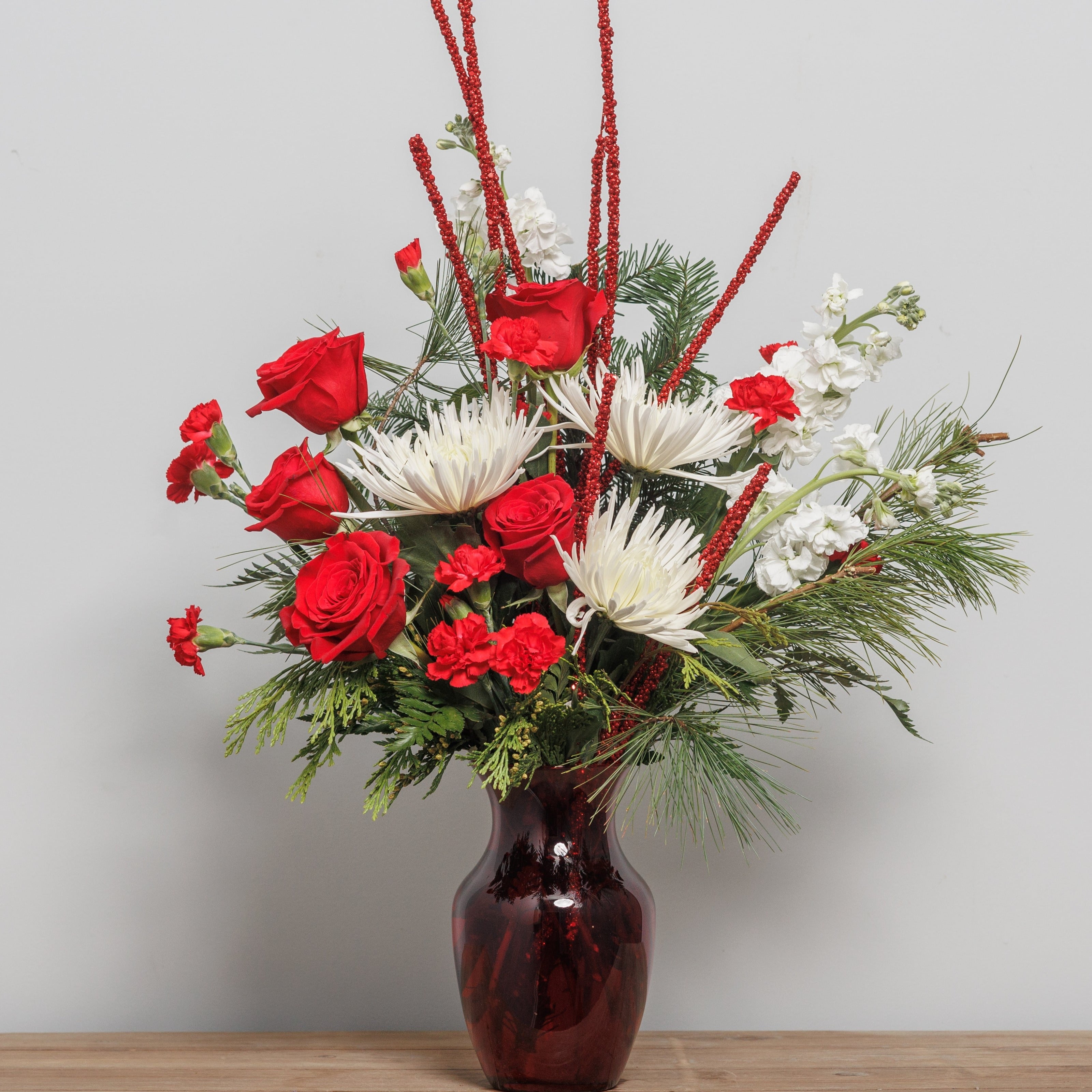 A white and red arrangement with glitter stems in a red vase.
