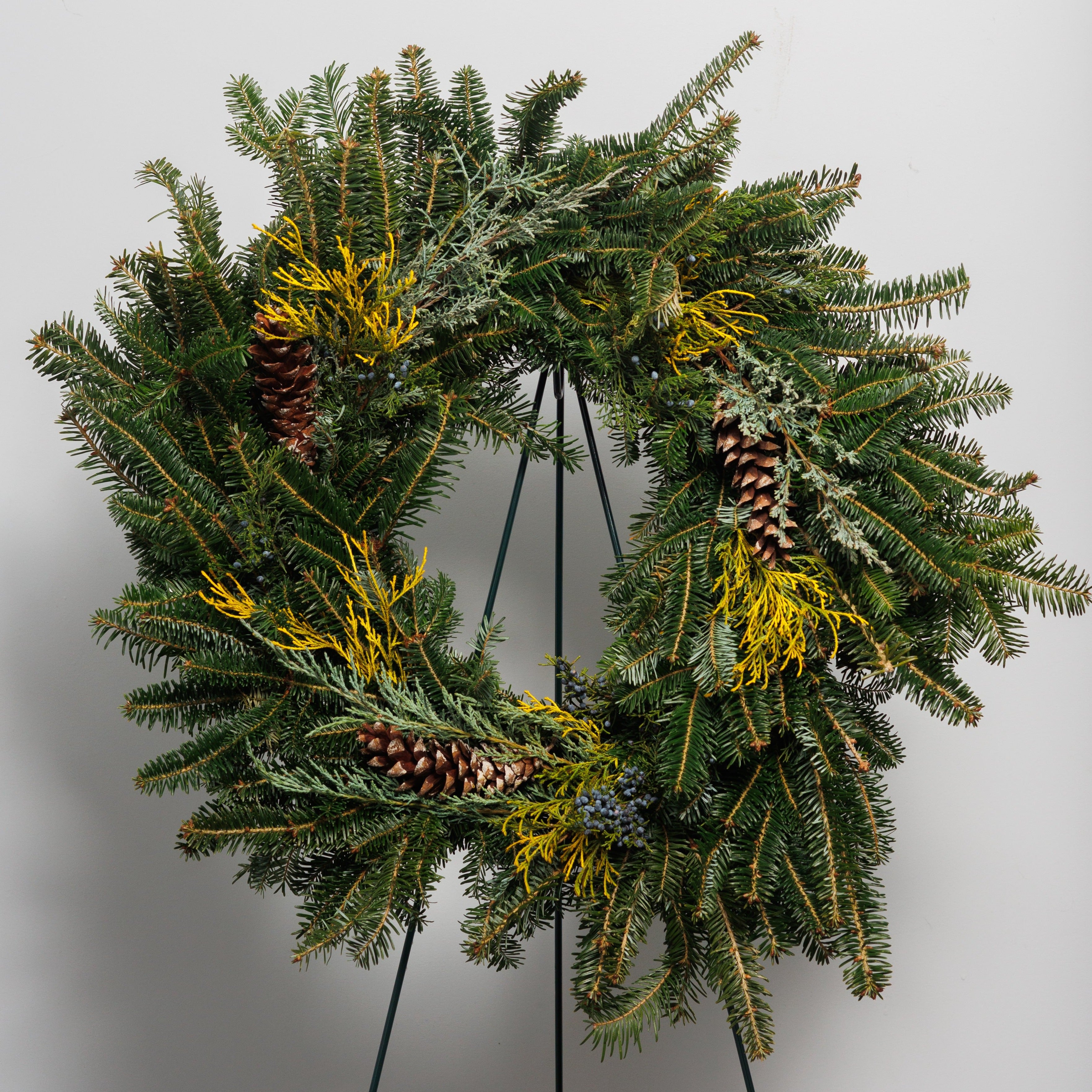 A mixed greens wreath with berries and cones.