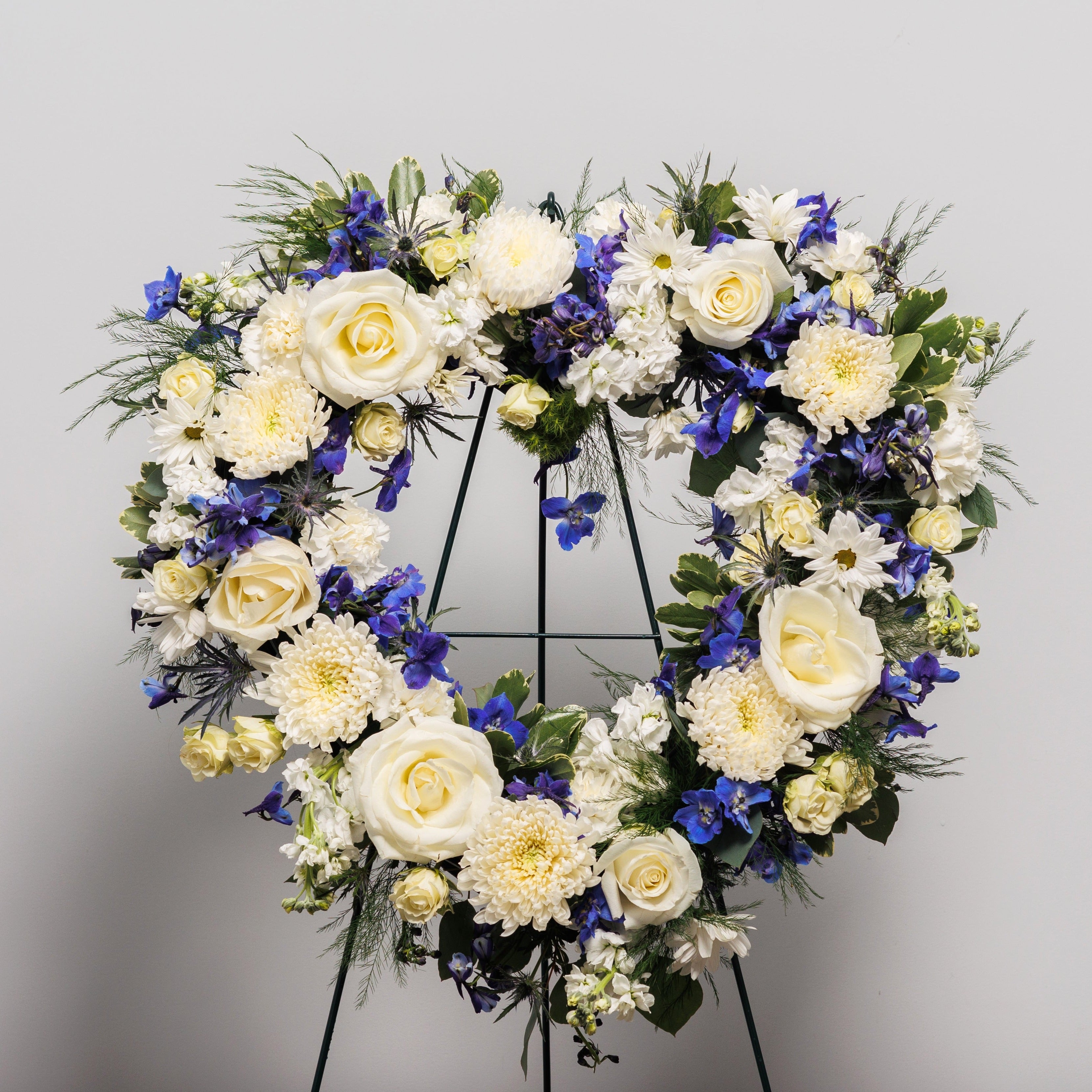 A standing heart spray with blue and white flowers.