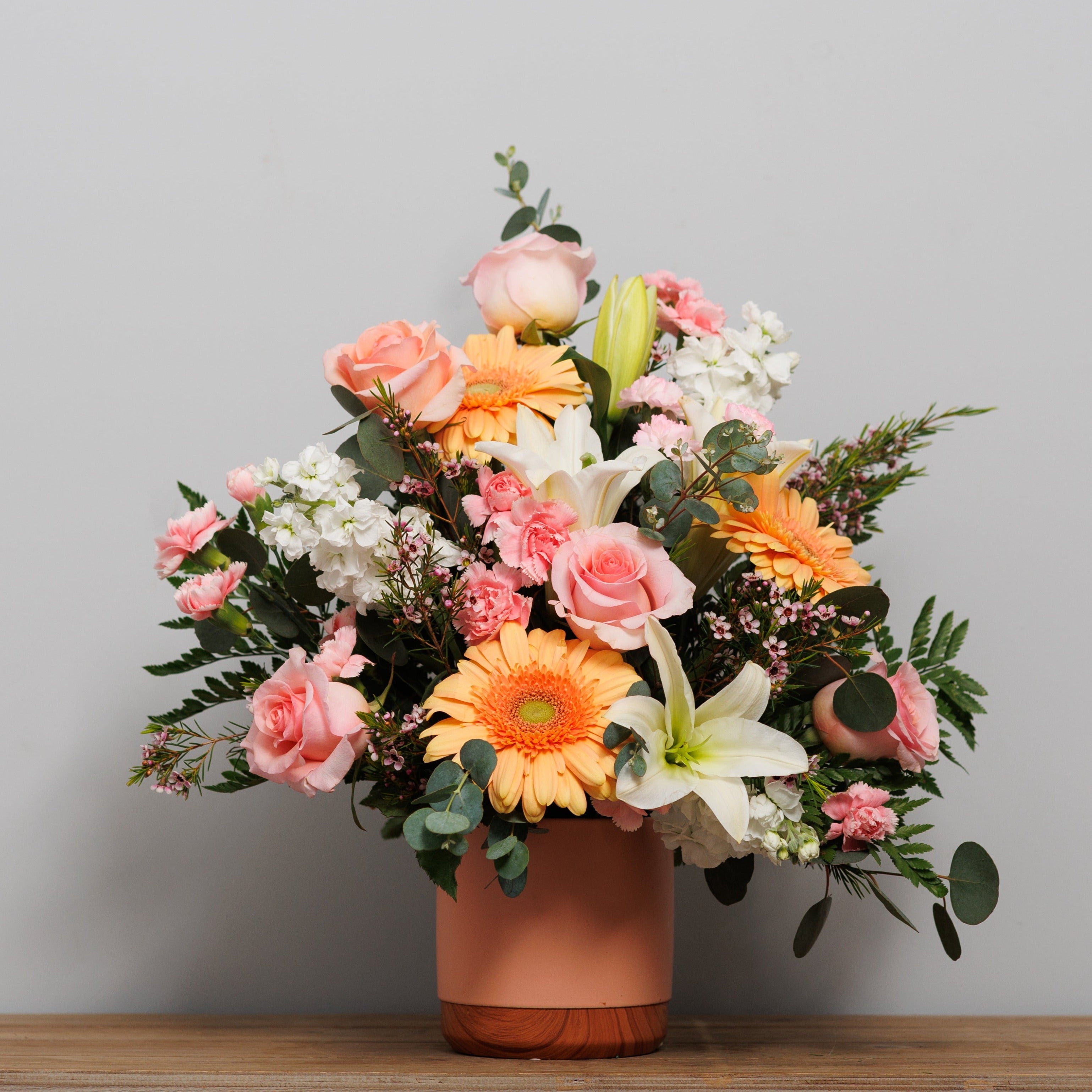 Peach and pink flower arrangement in a pot.