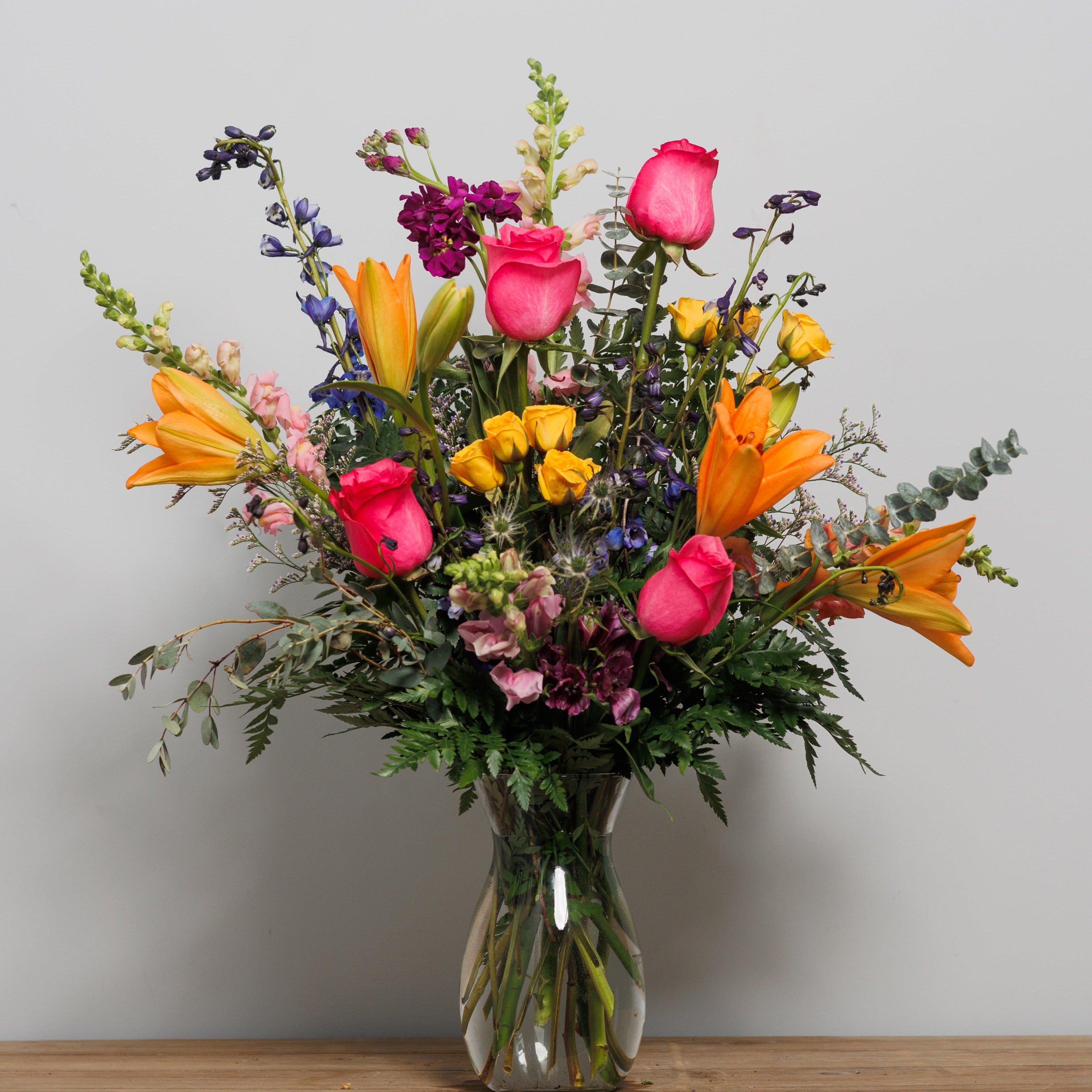 A bright arrangement with orange lilies and hot pink roses.