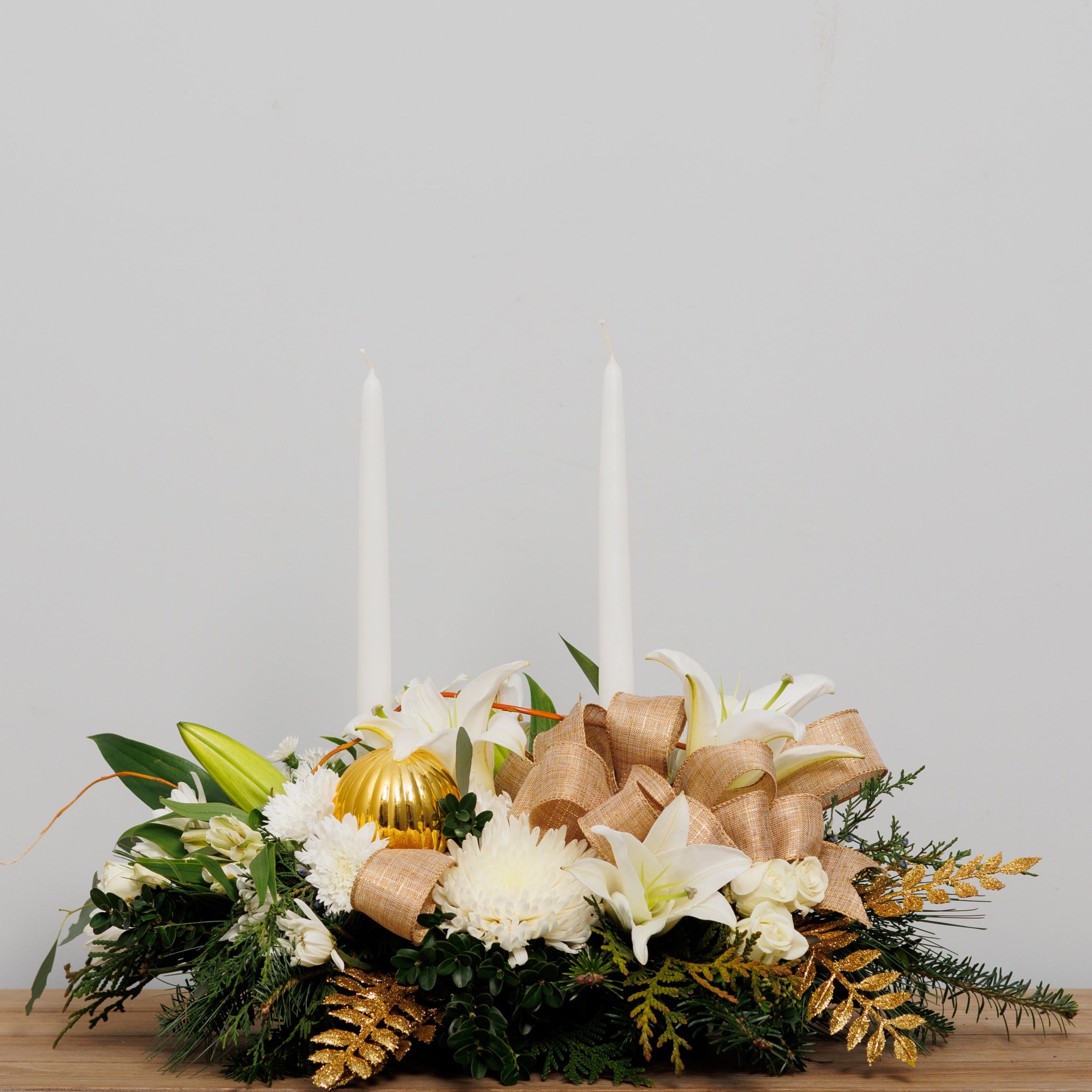 A white Christmas centerpiece with gold accents and two candles.
