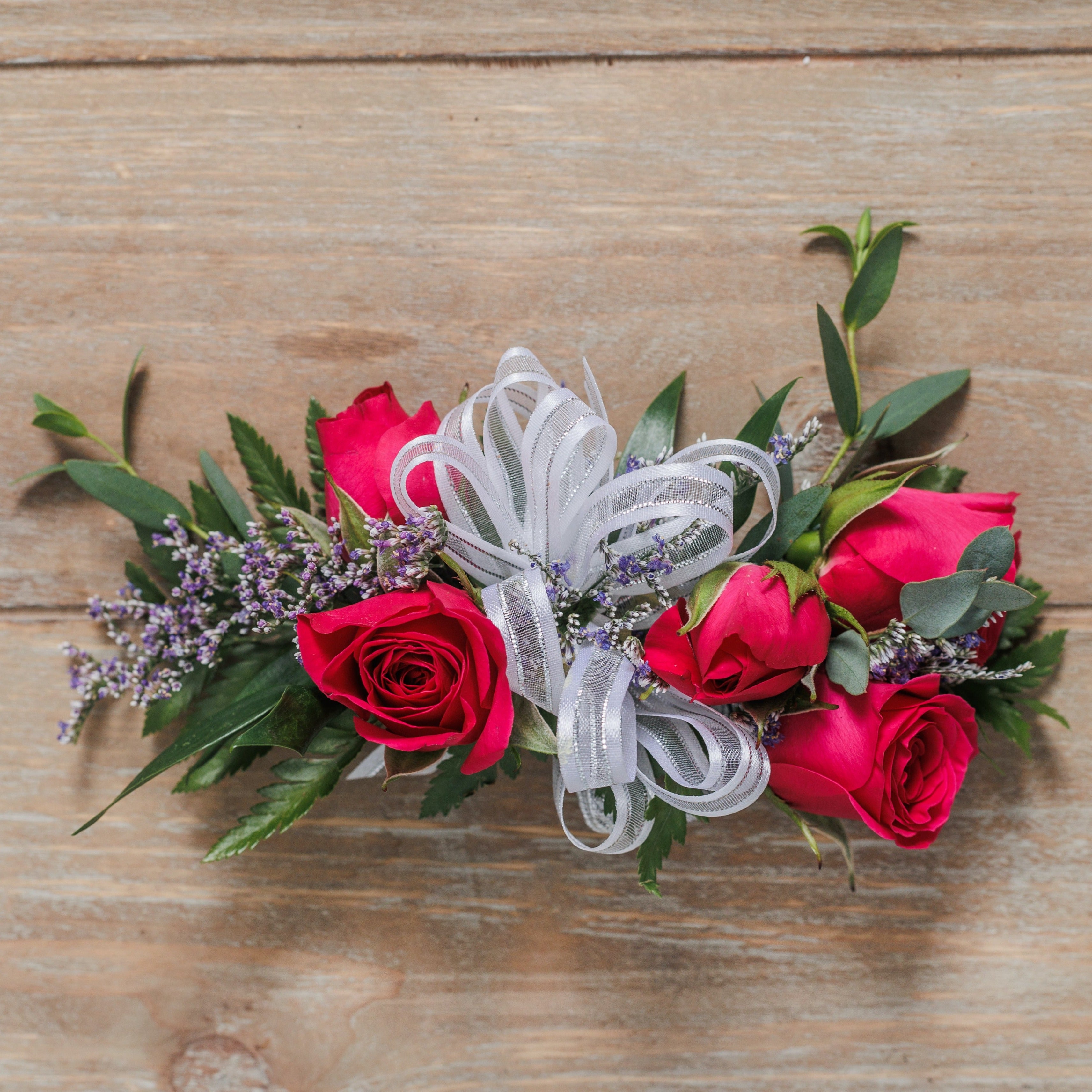 A wrist corsage with hot pink spray roses and silver ribbon.