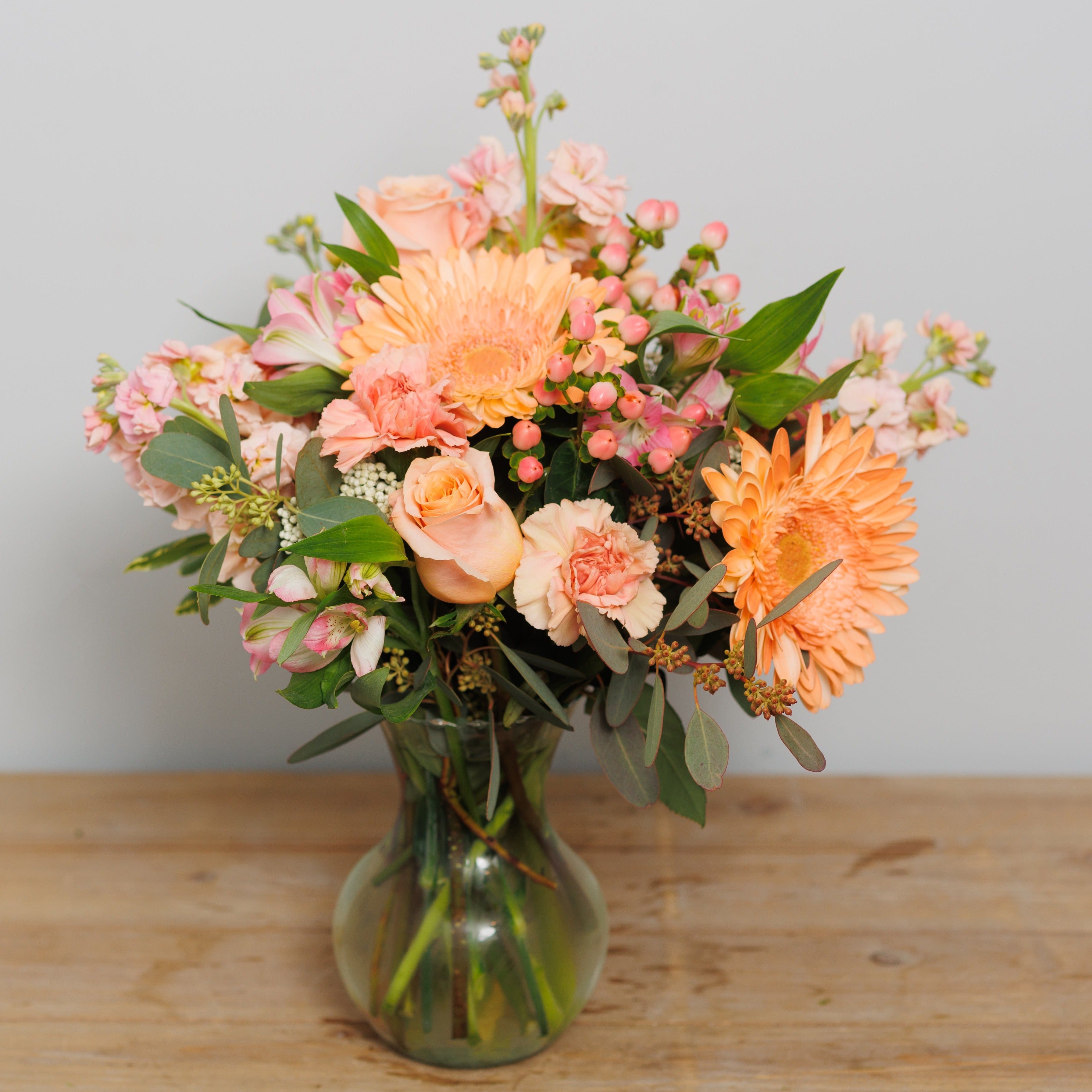 Shades of peach and pink flowers in a vase.