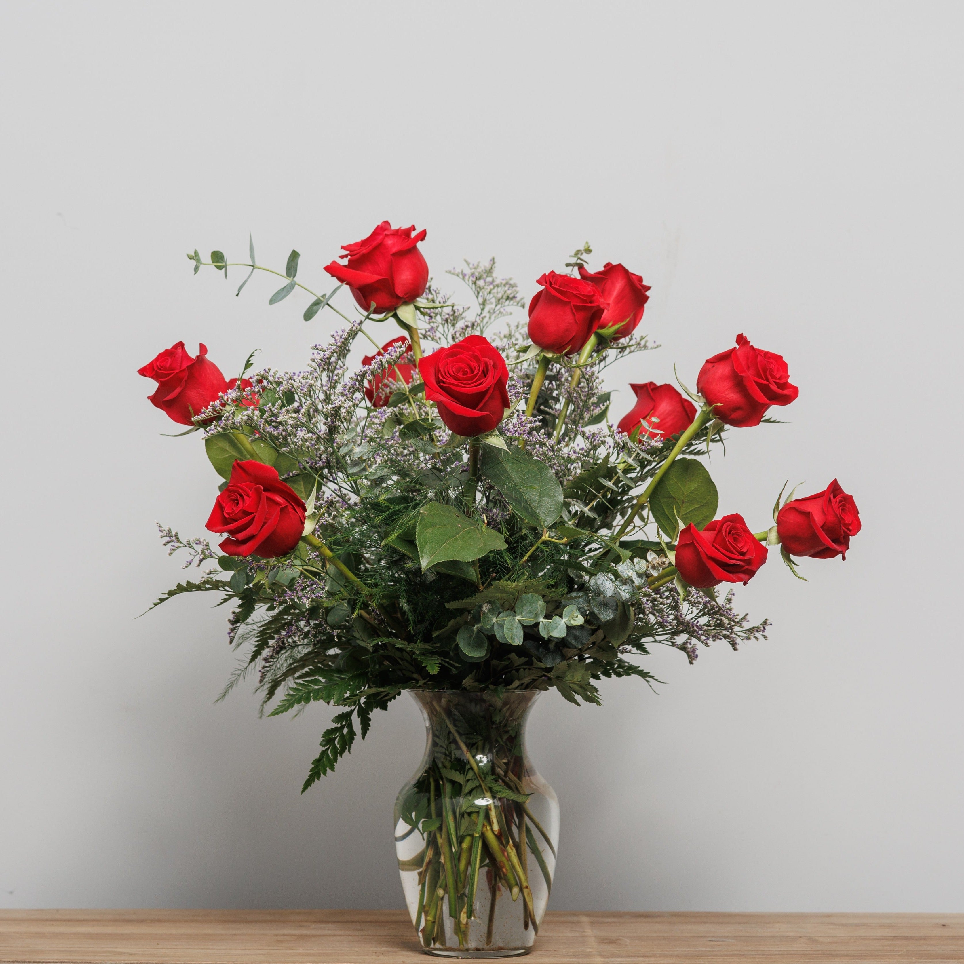 A dozen red roses arranged in a vase.