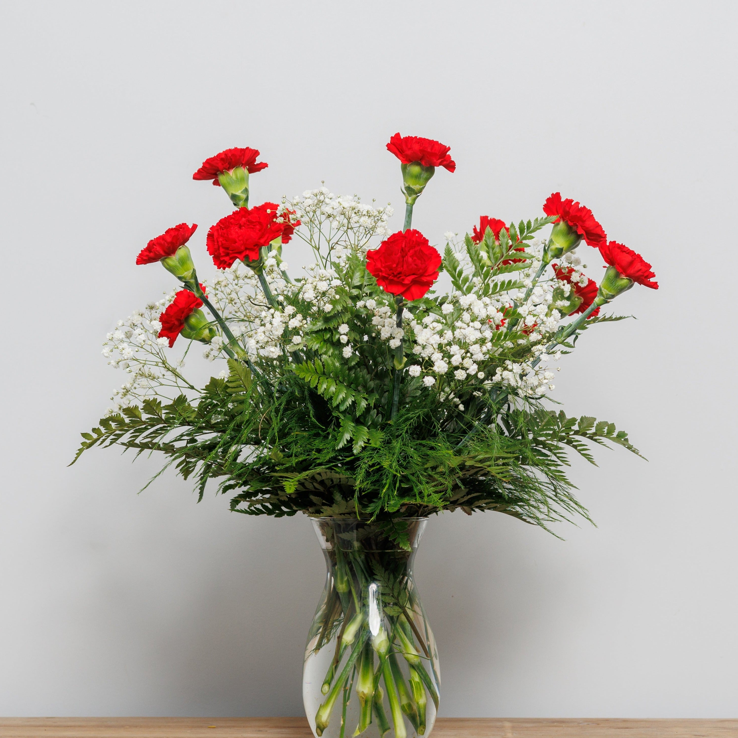 A vase arrangement with a dozen red carnations