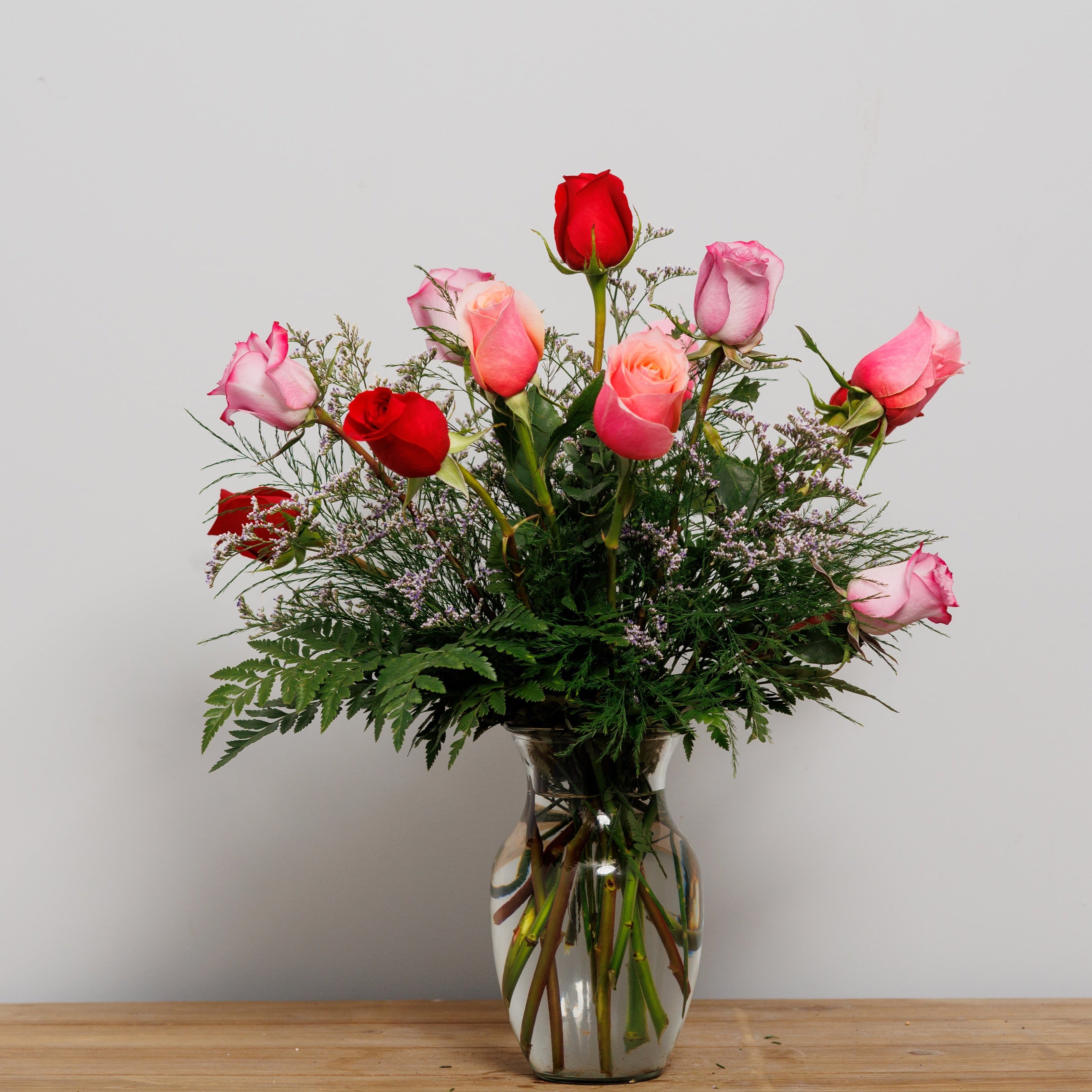 A dozen roses of mixed colors in a vase.