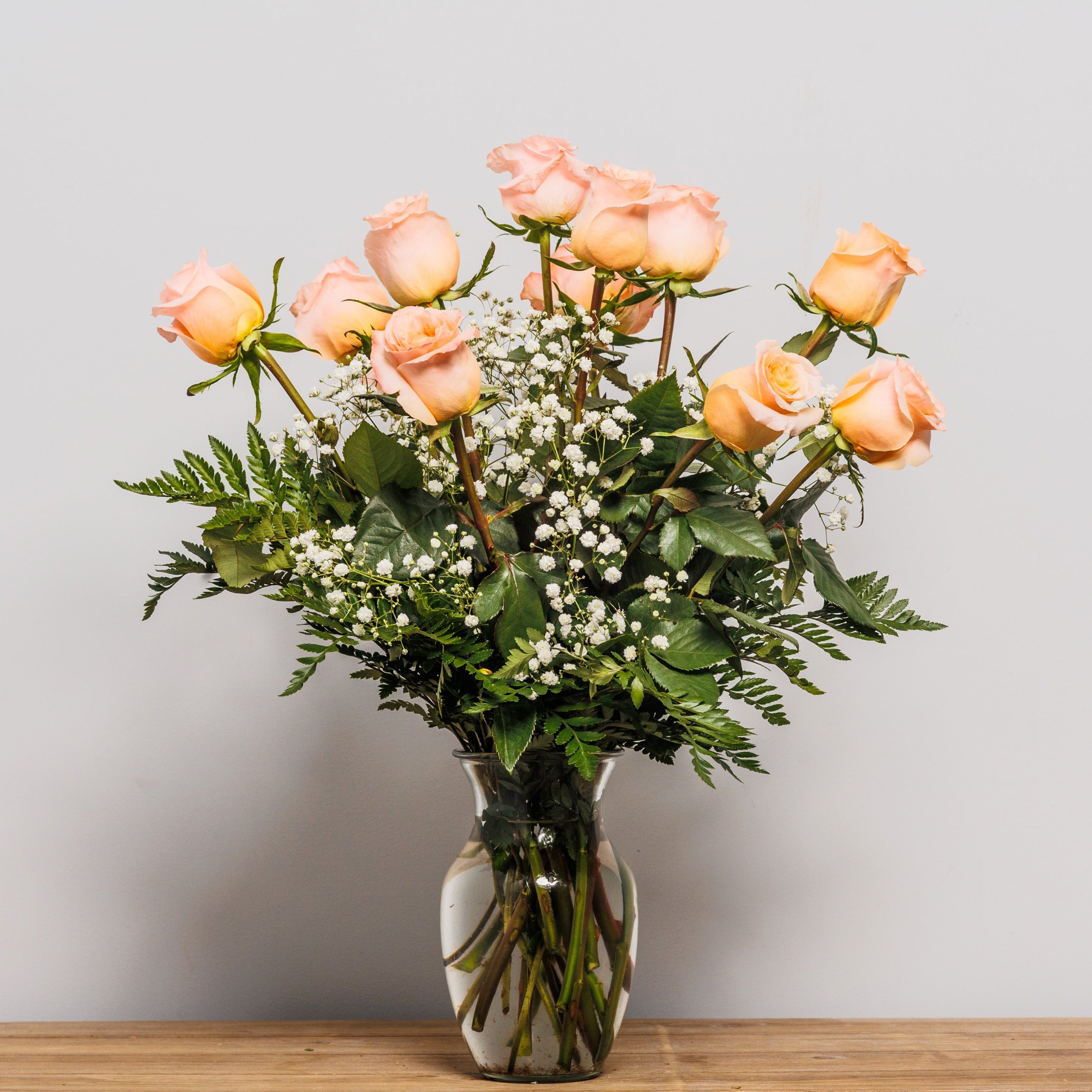 A dozen shimmer peach roses arranged in a vase.