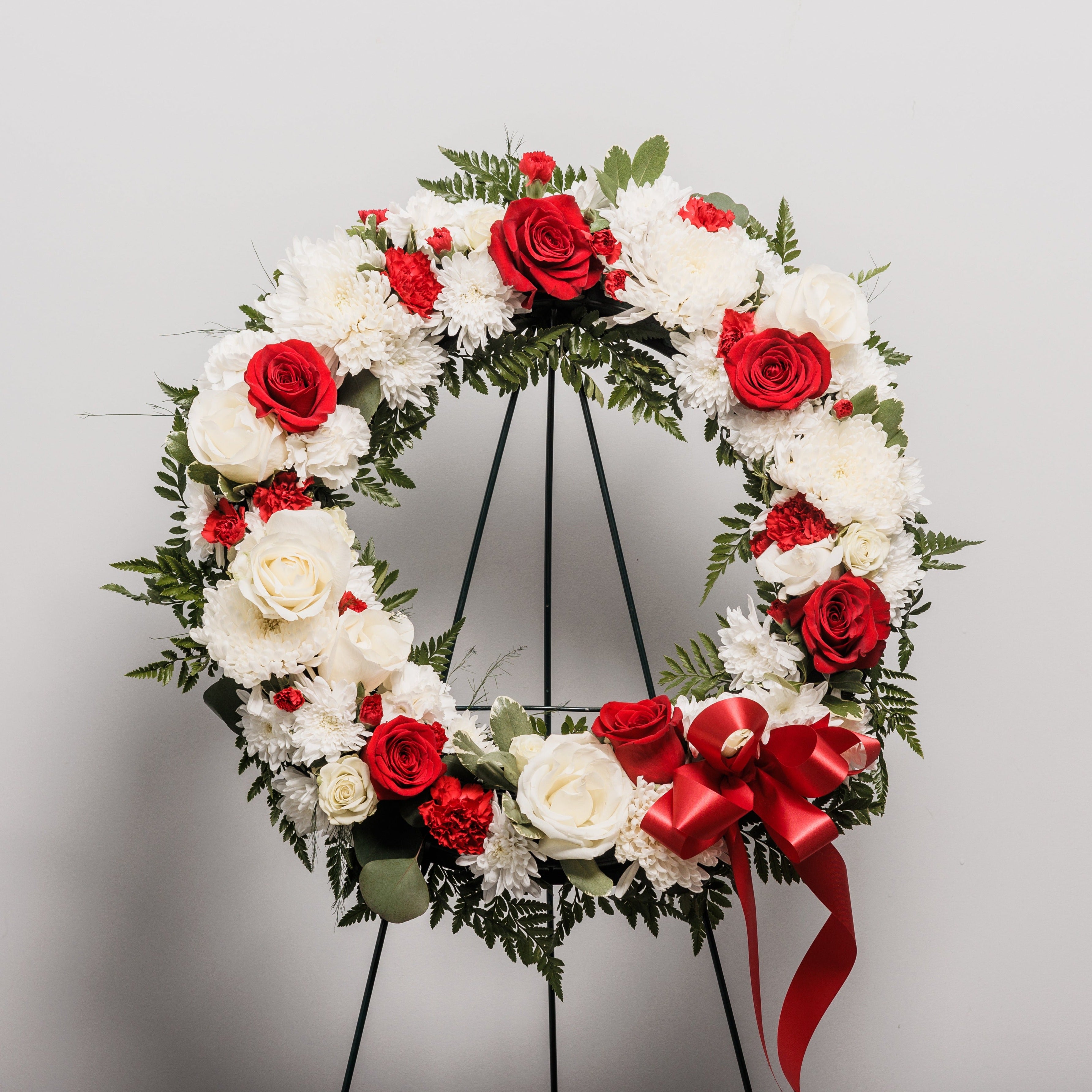 A wreath standing spray with white flowers and red roses.