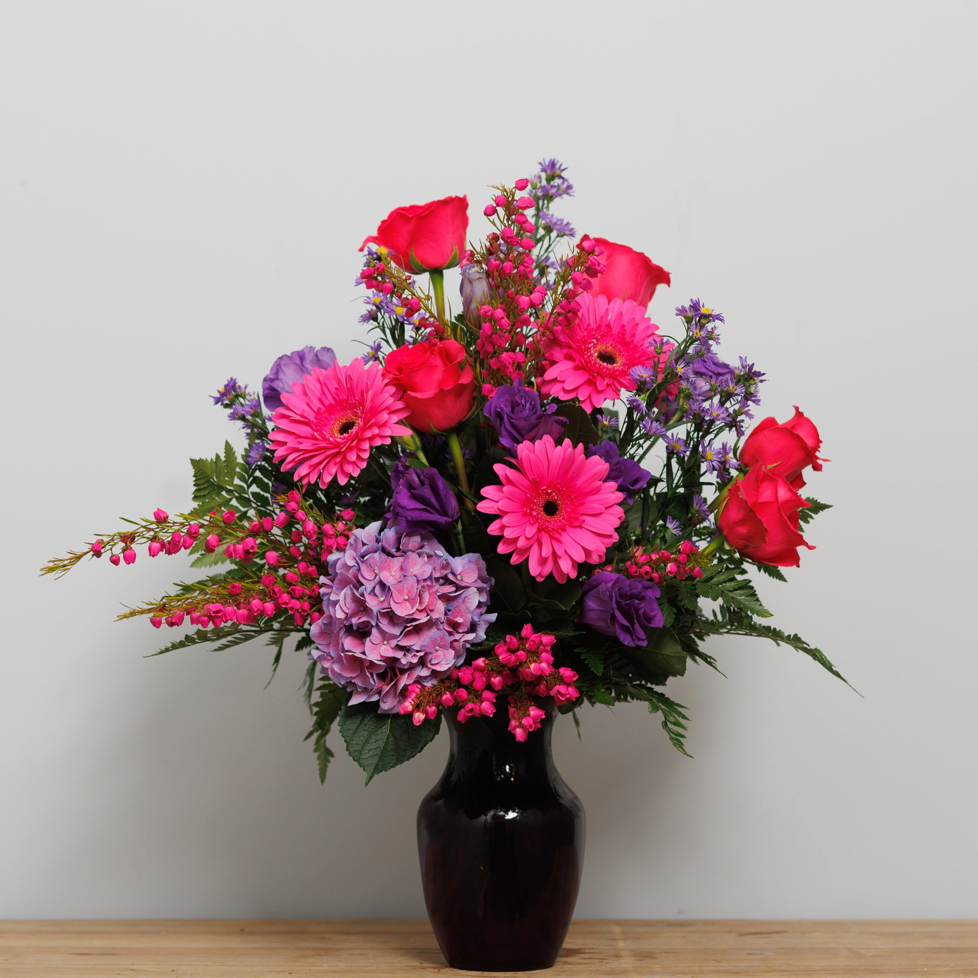 Hot pink and purple flowers in a purple vase.