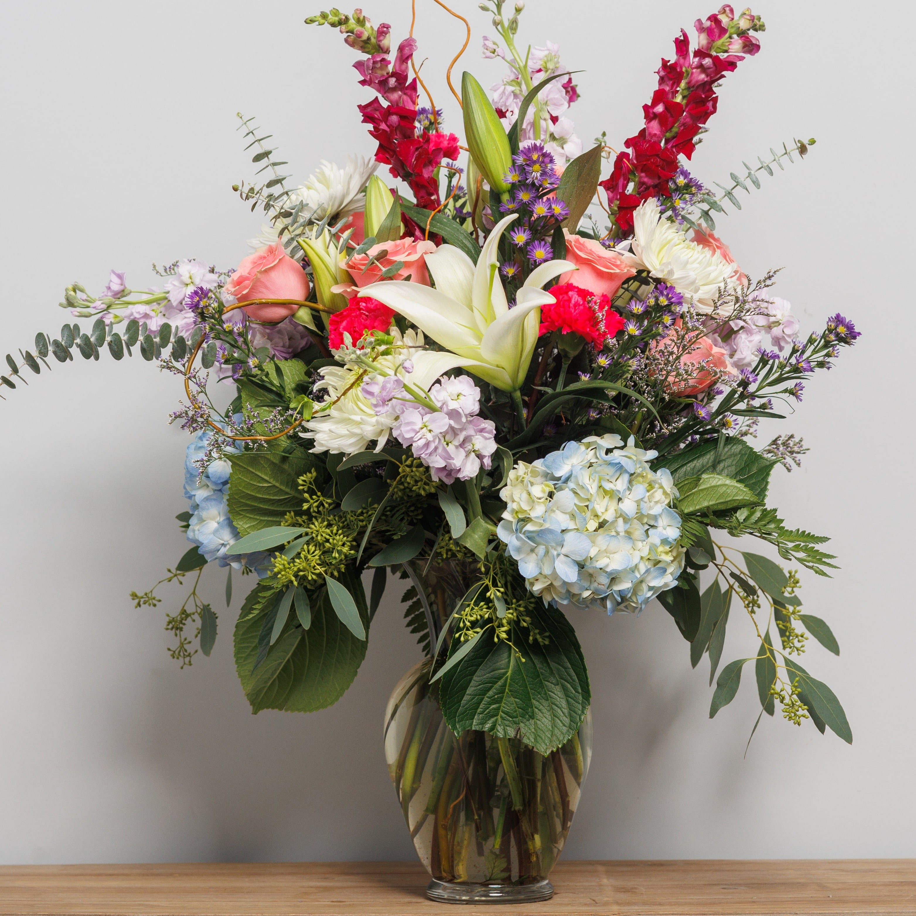 A large vase arrangement with an assortment of flowers and colors.