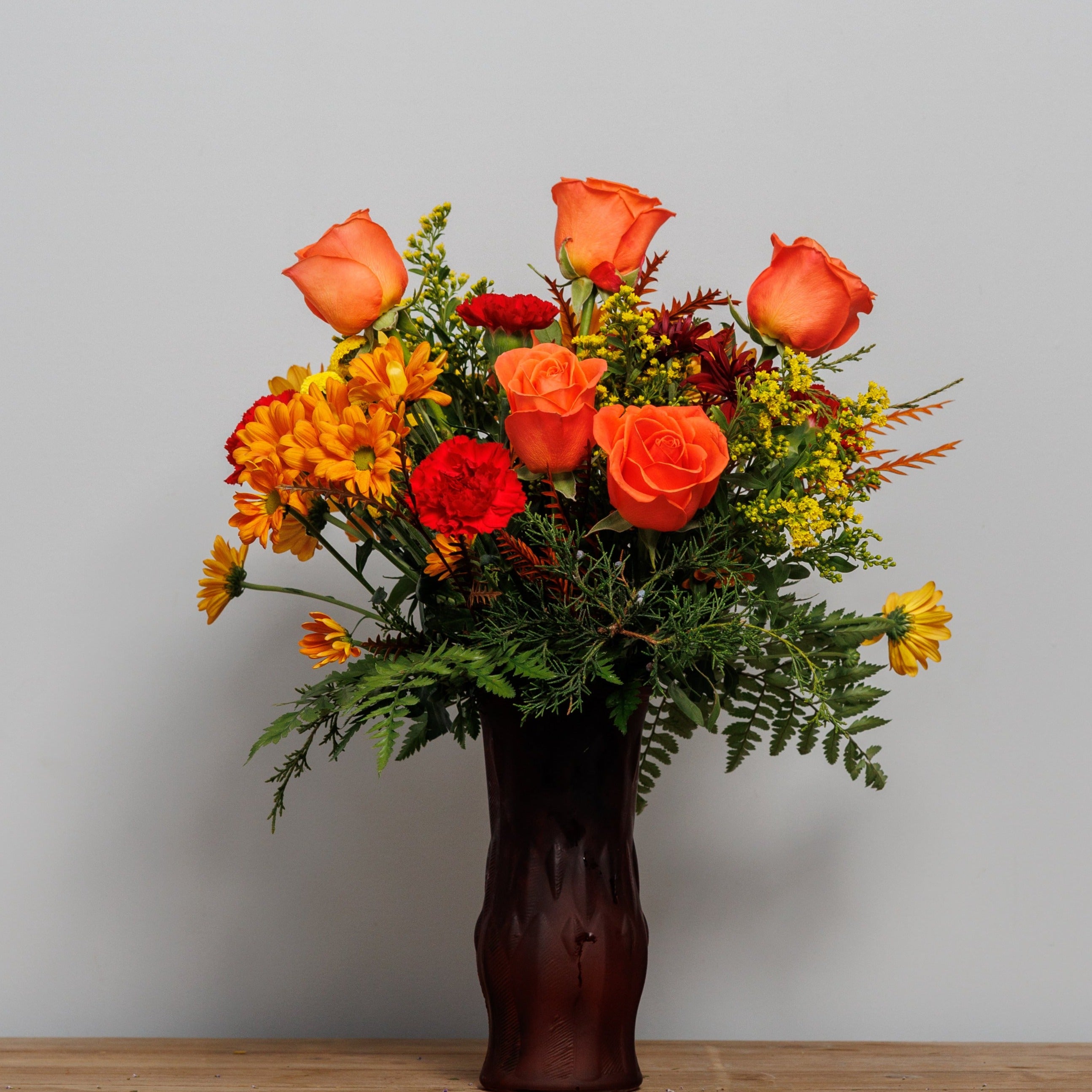 Orange roses with daisies and solidago.