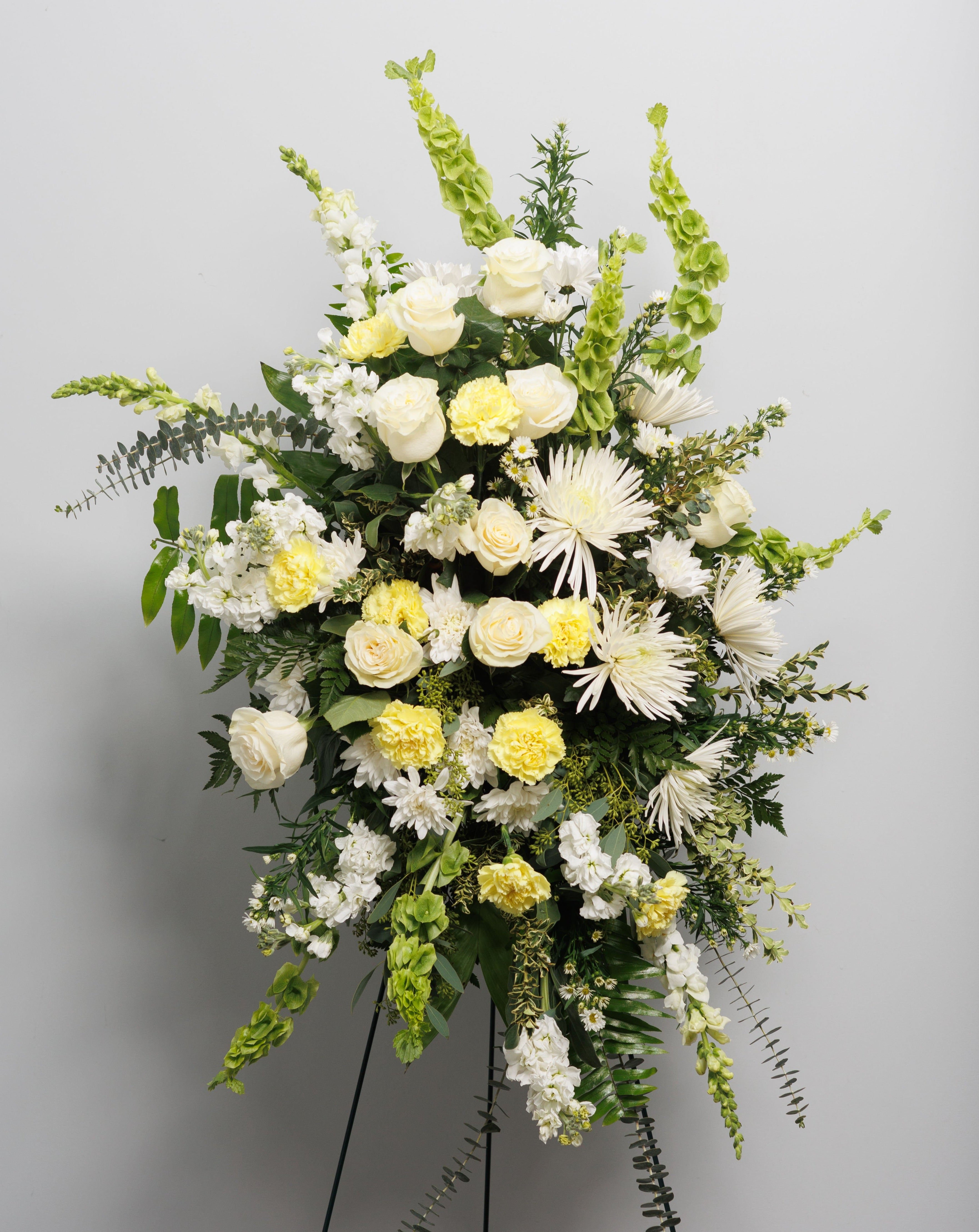 A standing spray with white, yellow and green flowers.