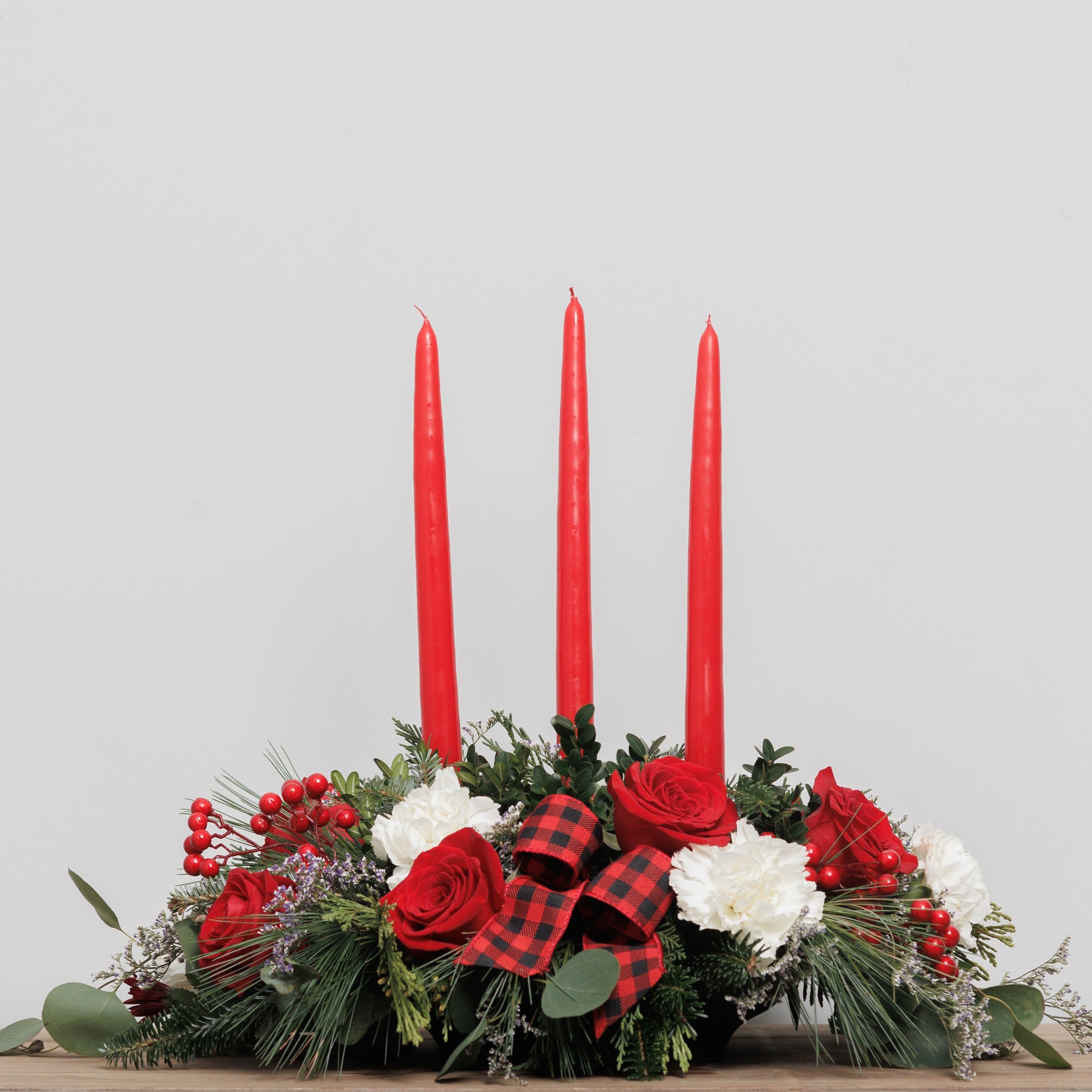 A red and white Christmas centerpiece with 3 red candles.
