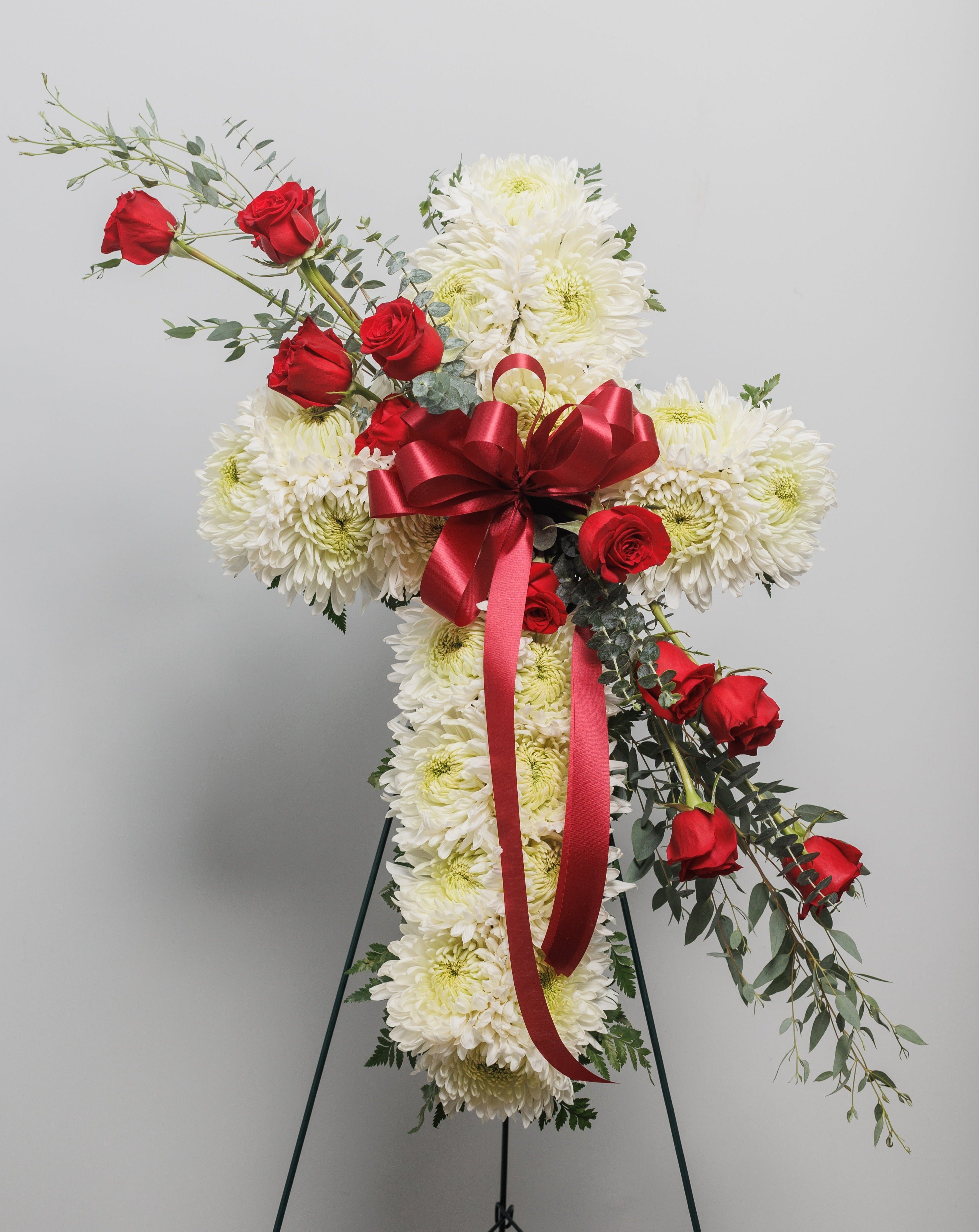 A cross spray with white mums and red roses.
