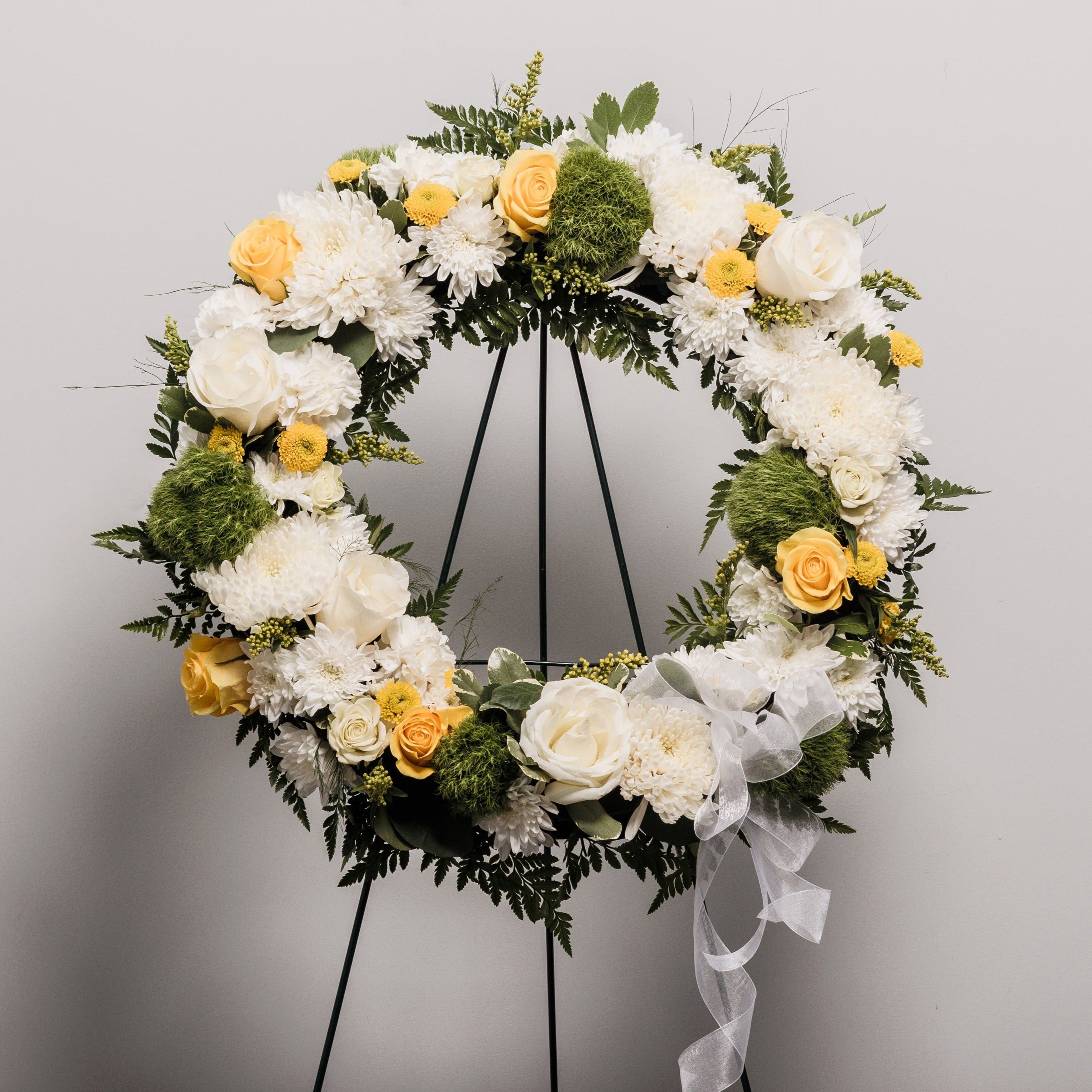 A wreath spray with white, yellow and green flowers.