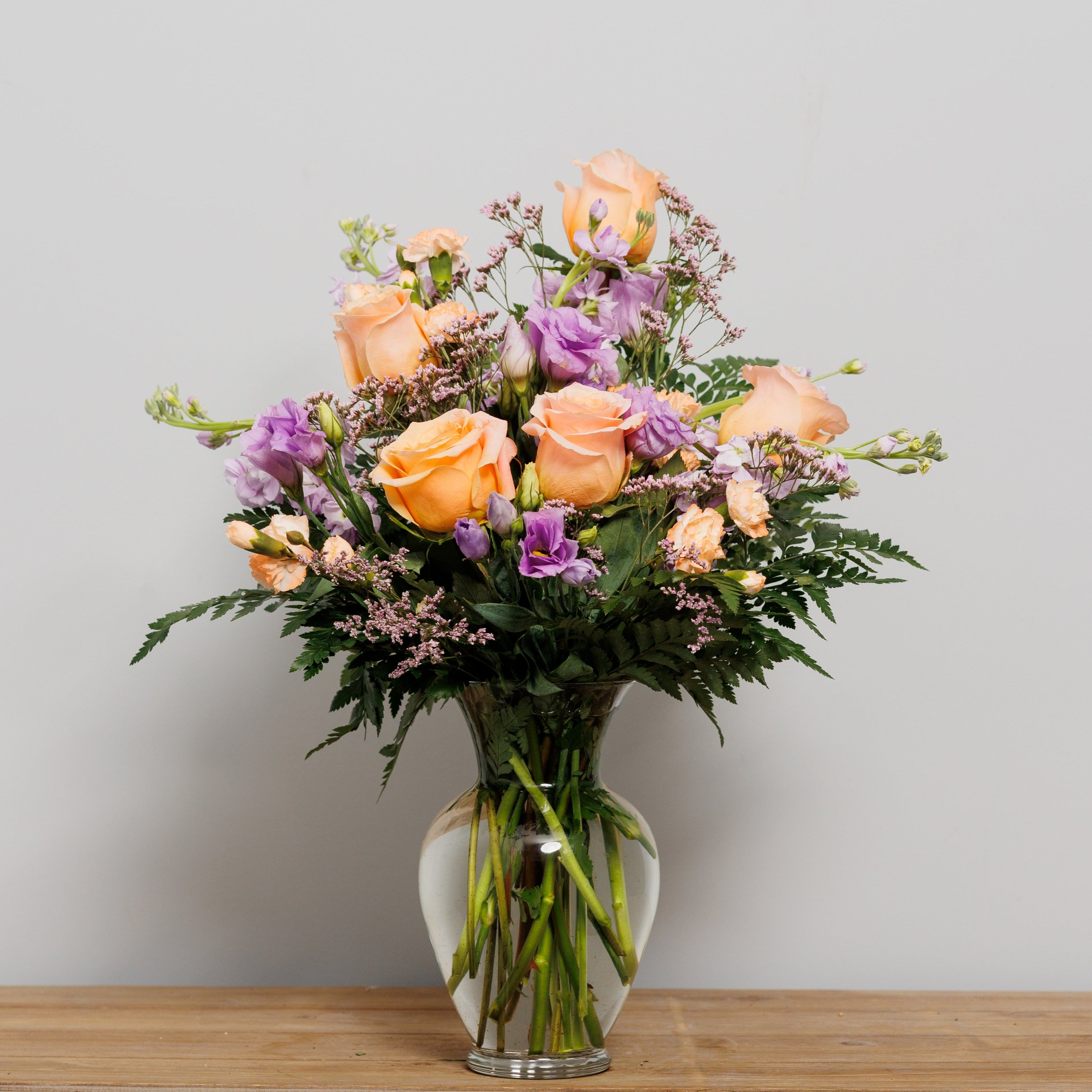 A vase arrangement with lavender and peach flowers.