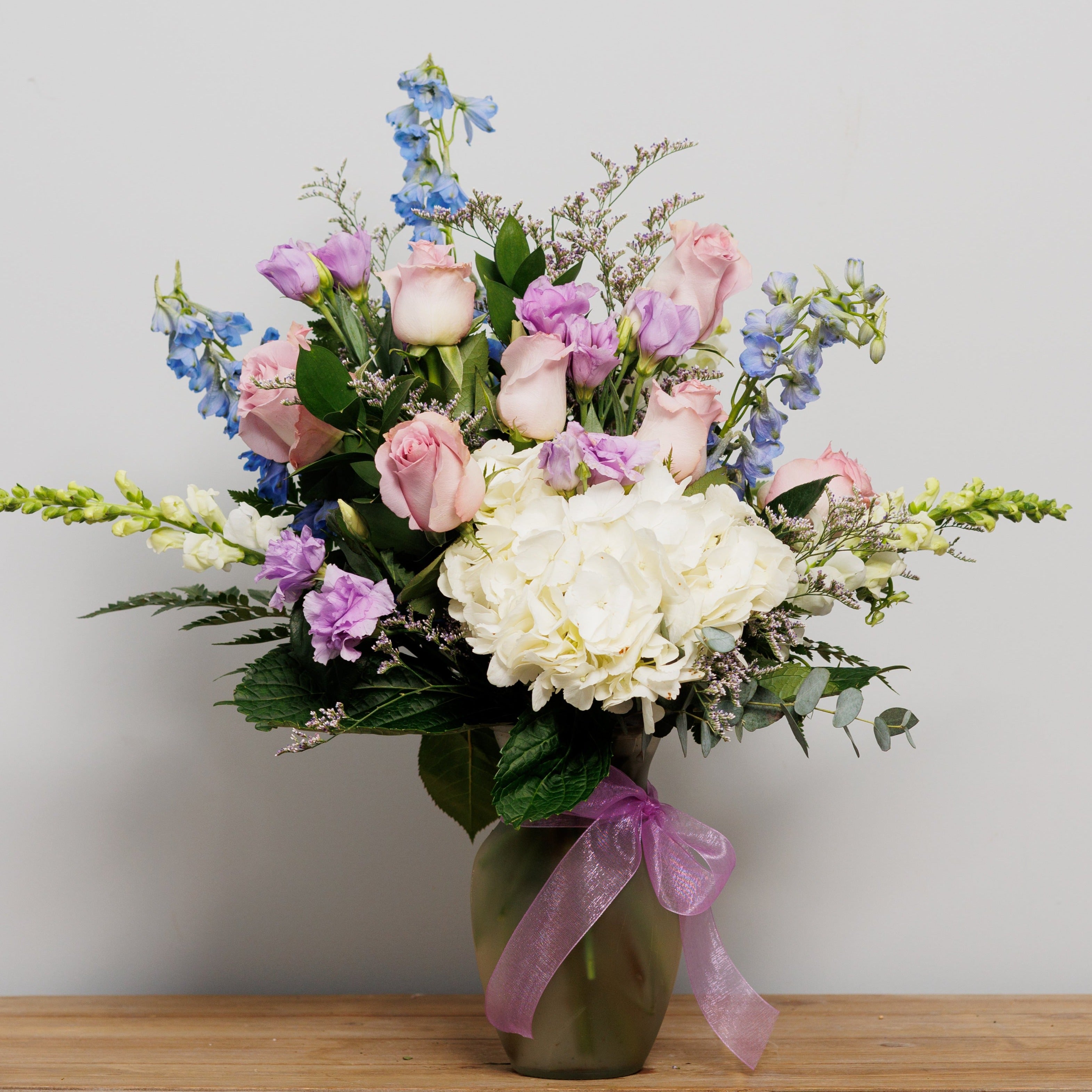 A flower arrangement with light blue, lavender and white.