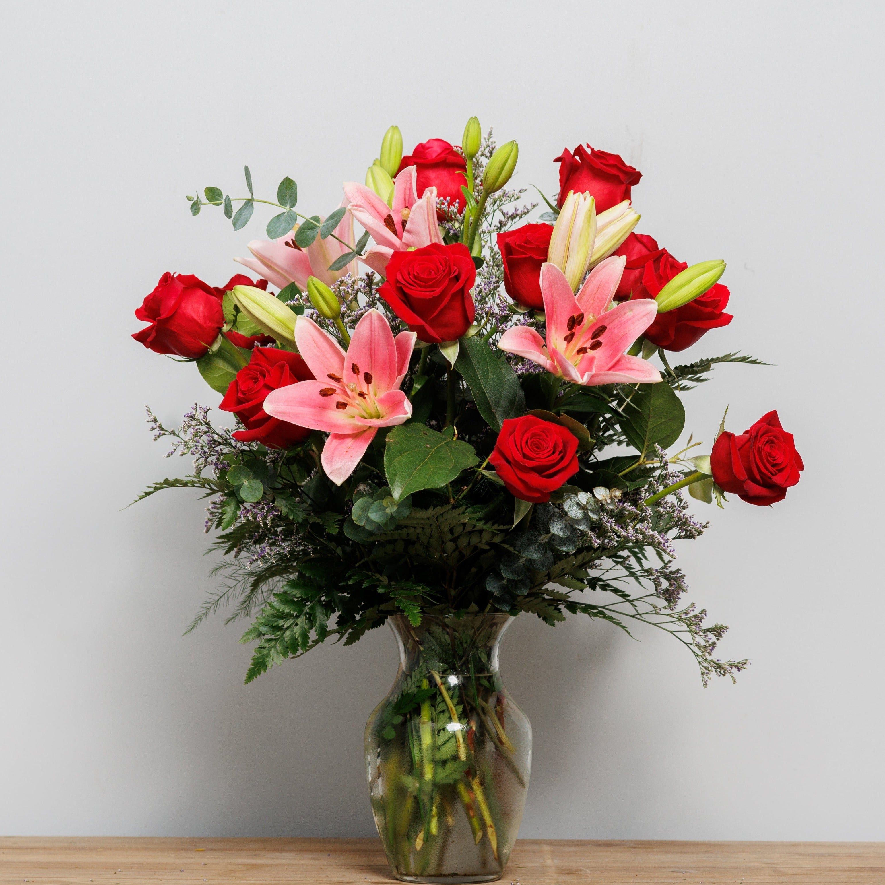 A vase arrangement with red roses and pink lilies.