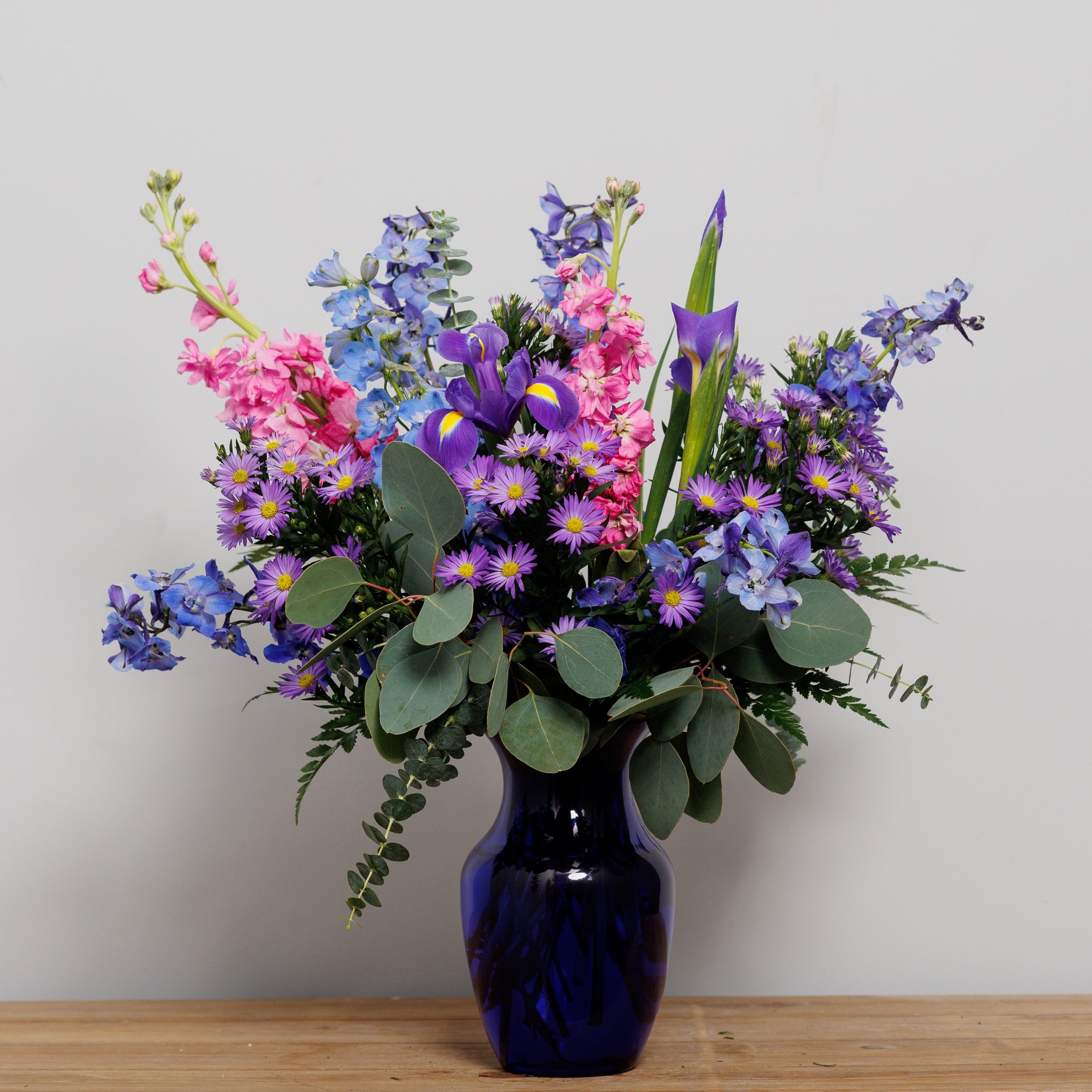 An all purple and blue arrangement in a blue vase.