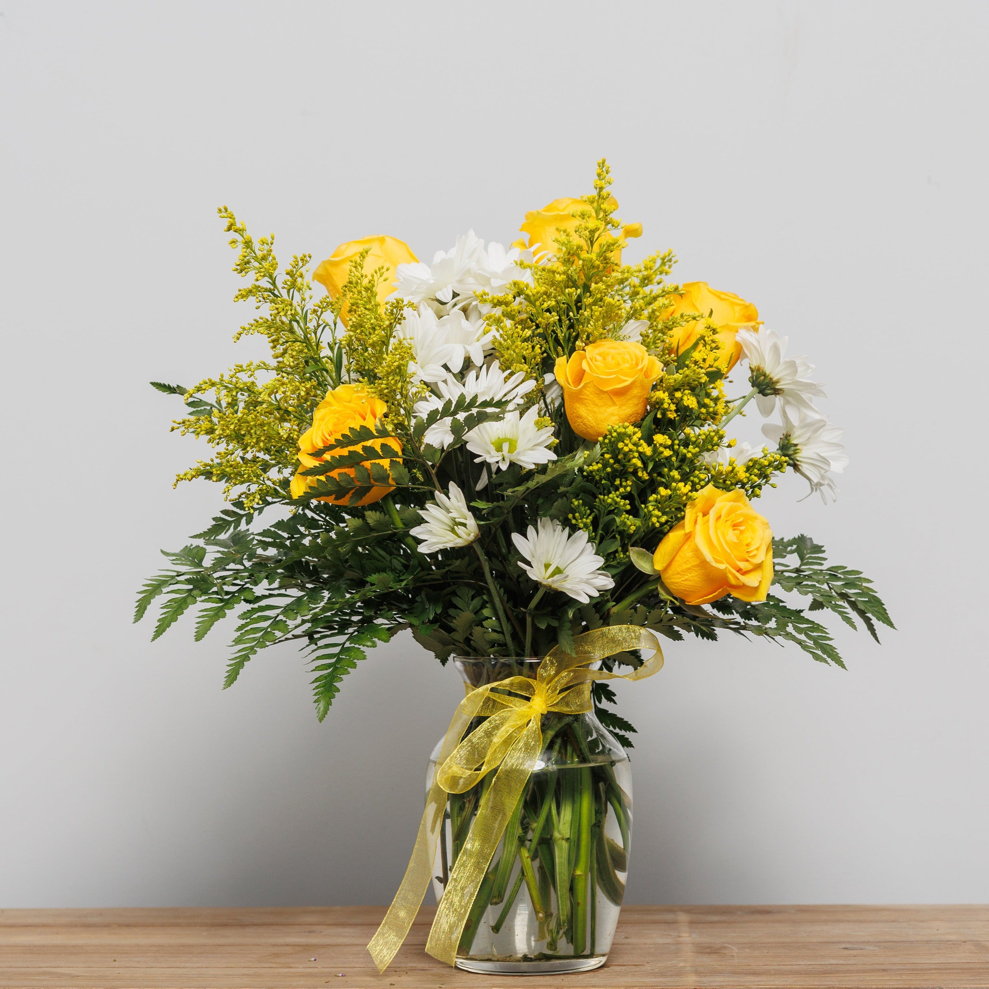 Yellow roses and white daisies arranged in a vase.